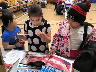 Students from Mangilaluk School examine oral health resources during the Tuktoyaktuk Community Health Fair, February 2020